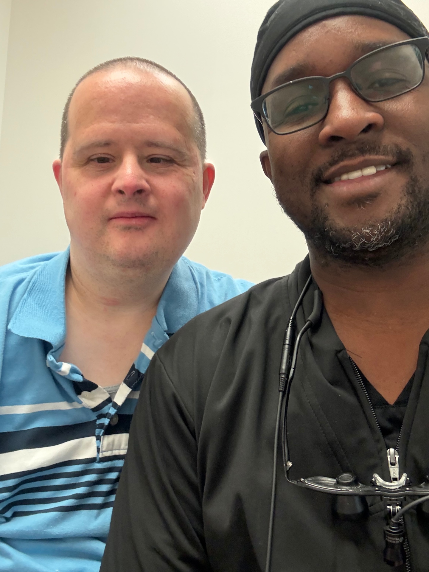 Dr. Baawo with a patient in a striped polo